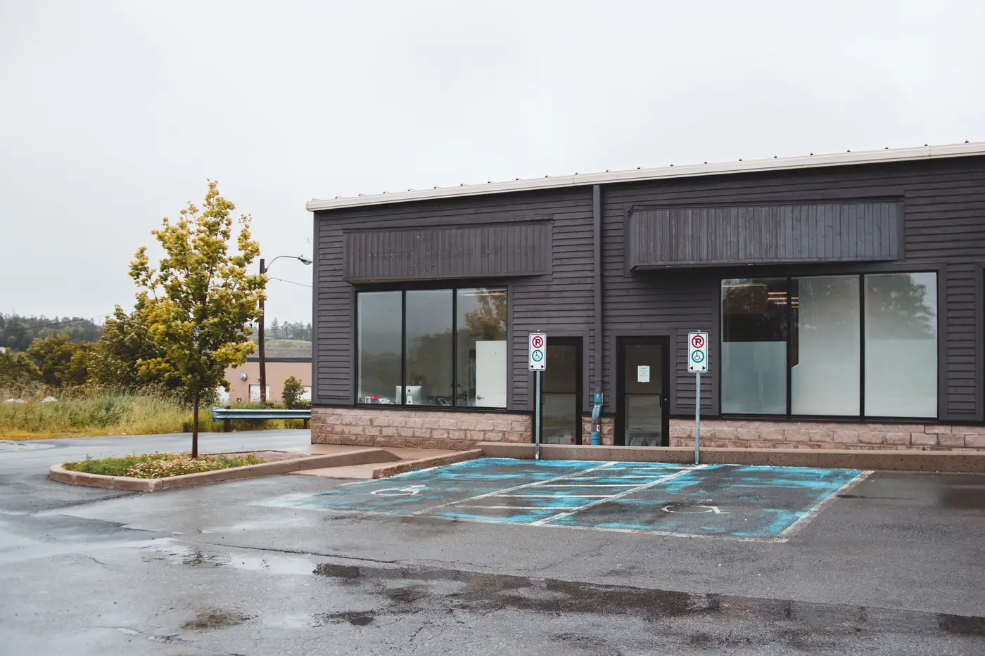 A newly built retail building with large windows and an empty striped parking lot.