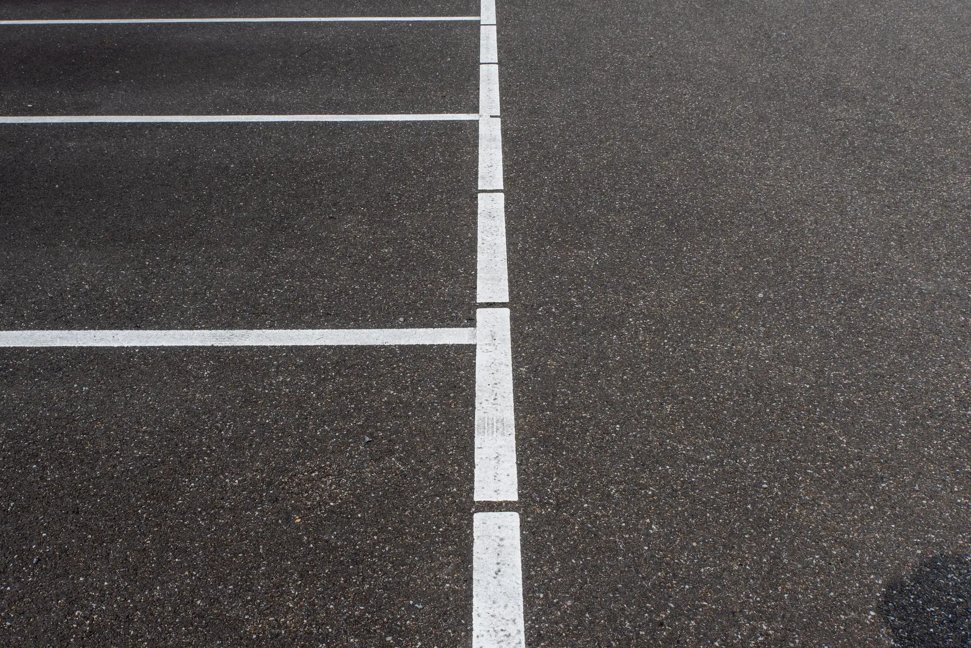 Freshly painted white stall lines on dark asphalt in an empty parking lot